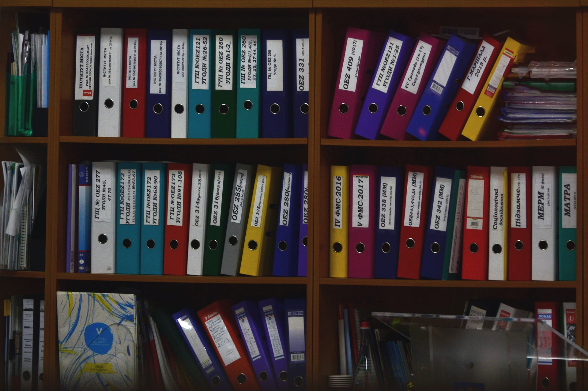 Some colorful files on an office shelf